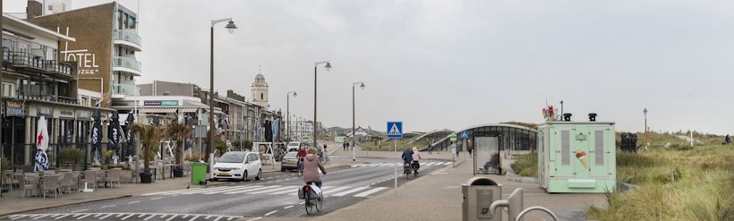a person riding a bicycle on a road with buildings on either side